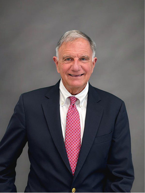 Smiling older man in navy suit, pink tie